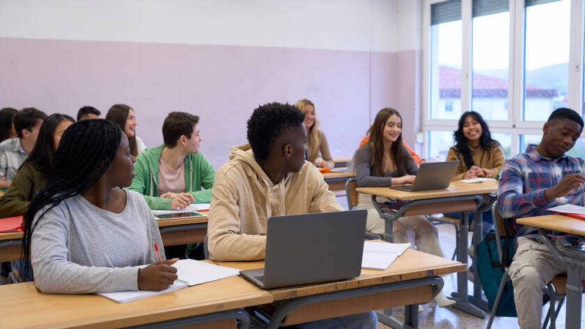 High school multiethnic students are listening to the teacher and taking notes during a lesson in a classroom